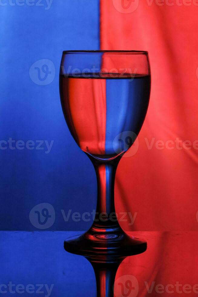 une du vin verre rempli avec l'eau sur une bicolore Contexte crée lumière diffraction et réflexion photo