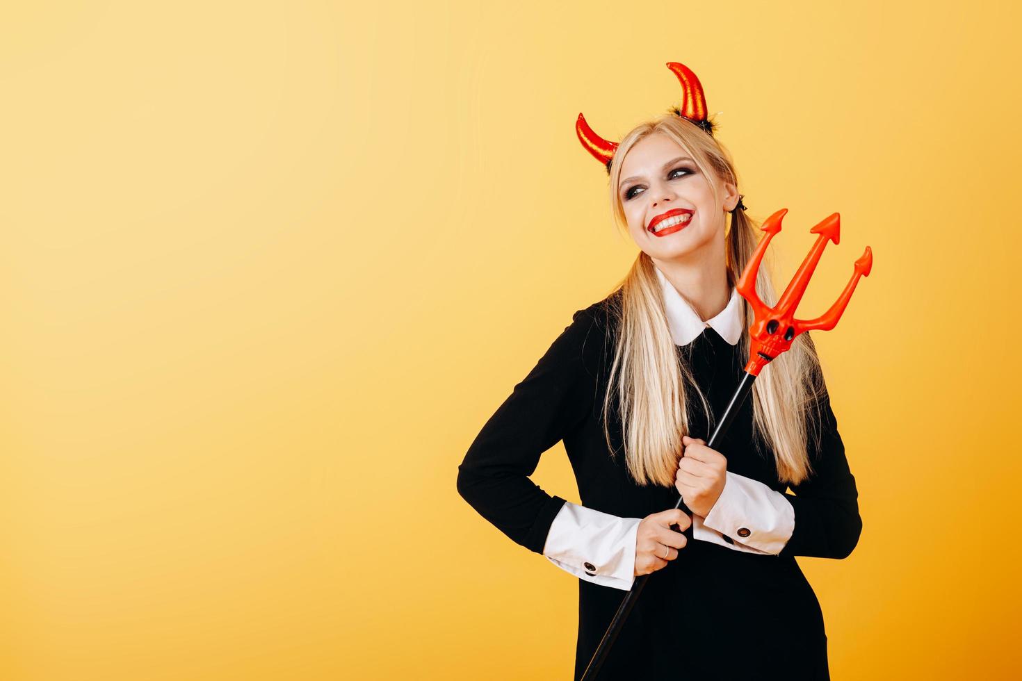 émotion heureuse de la femme du diable debout sur un fond jaune. photo