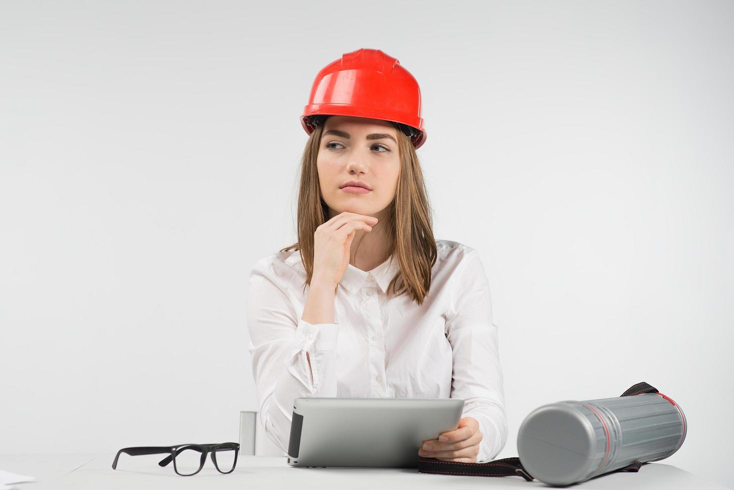 femme spéculer est assise à la table dans un casque orange détient ipad photo