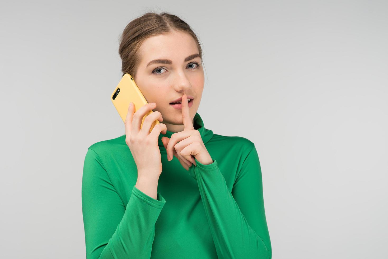 jolie jeune femme parlant sur un téléphone portable le tenant dans ses mains. appel au silence photo