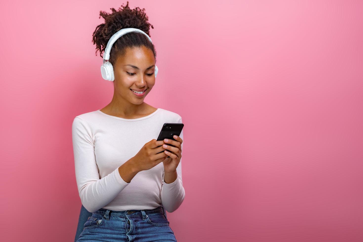 portrait d'une fille dans des écouteurs et tenant un téléphone portable regardant l'écran - image photo