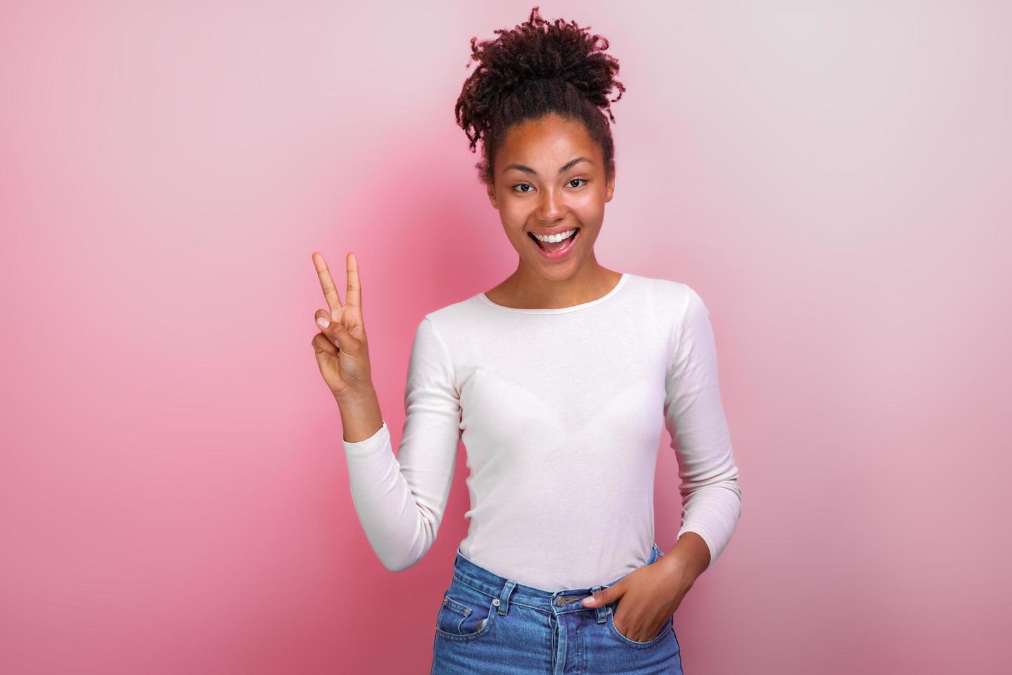 jolie jeune femme montrant le geste de la victoire et regarde joyeusement photo