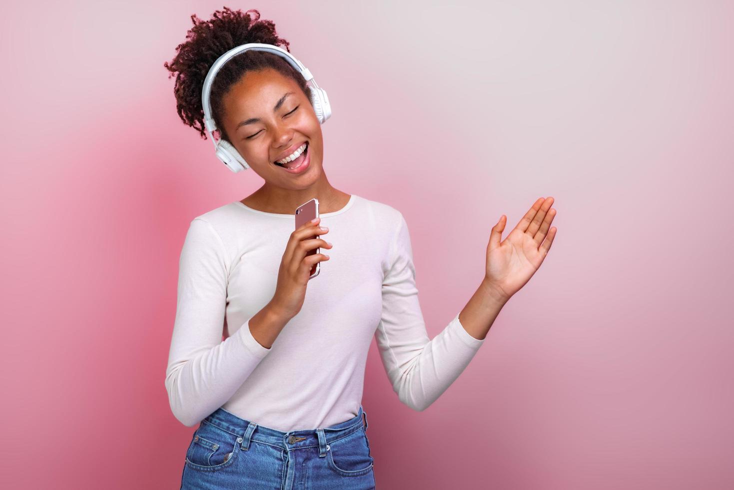 Jeune fille dans des écouteurs tenant un téléphone portable chantant avec une émotion heureuse - image photo