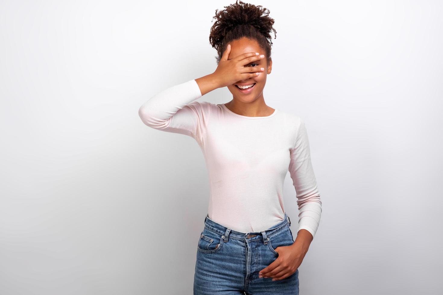 femme ferma les yeux avec son bras et regardant de manière ludique à travers les doigts debout dans le studio - image photo