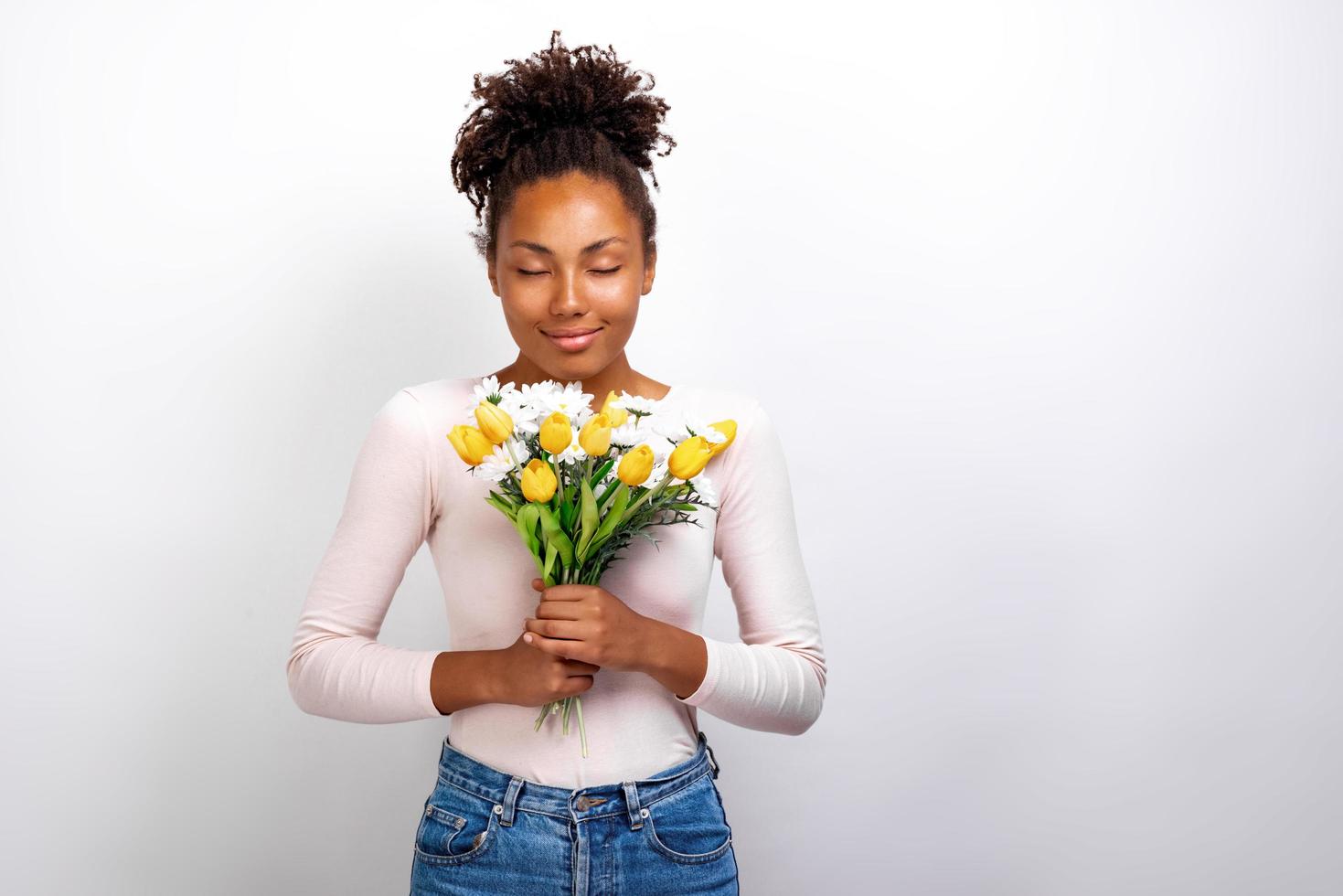 portrait en studio demi-longueur d'une fille merveilleuse avec un bouquet de fleurs de tulipes et de marguerites dans ses mains photo
