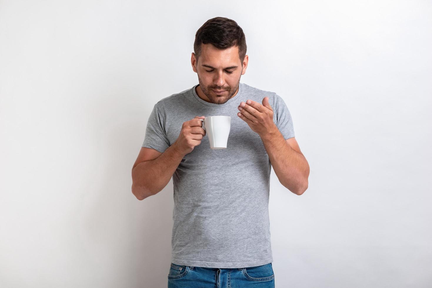 bel homme se tient avec une tasse de thé ou de café du matin et sent l'arôme.- image photo