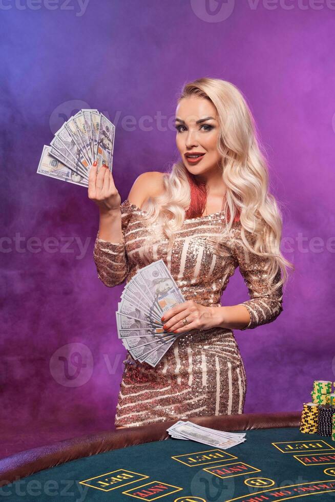 blond femme avec une parfait coiffure et brillant maquillage est posant avec en jouant cartes dans sa mains. casino, poker. photo