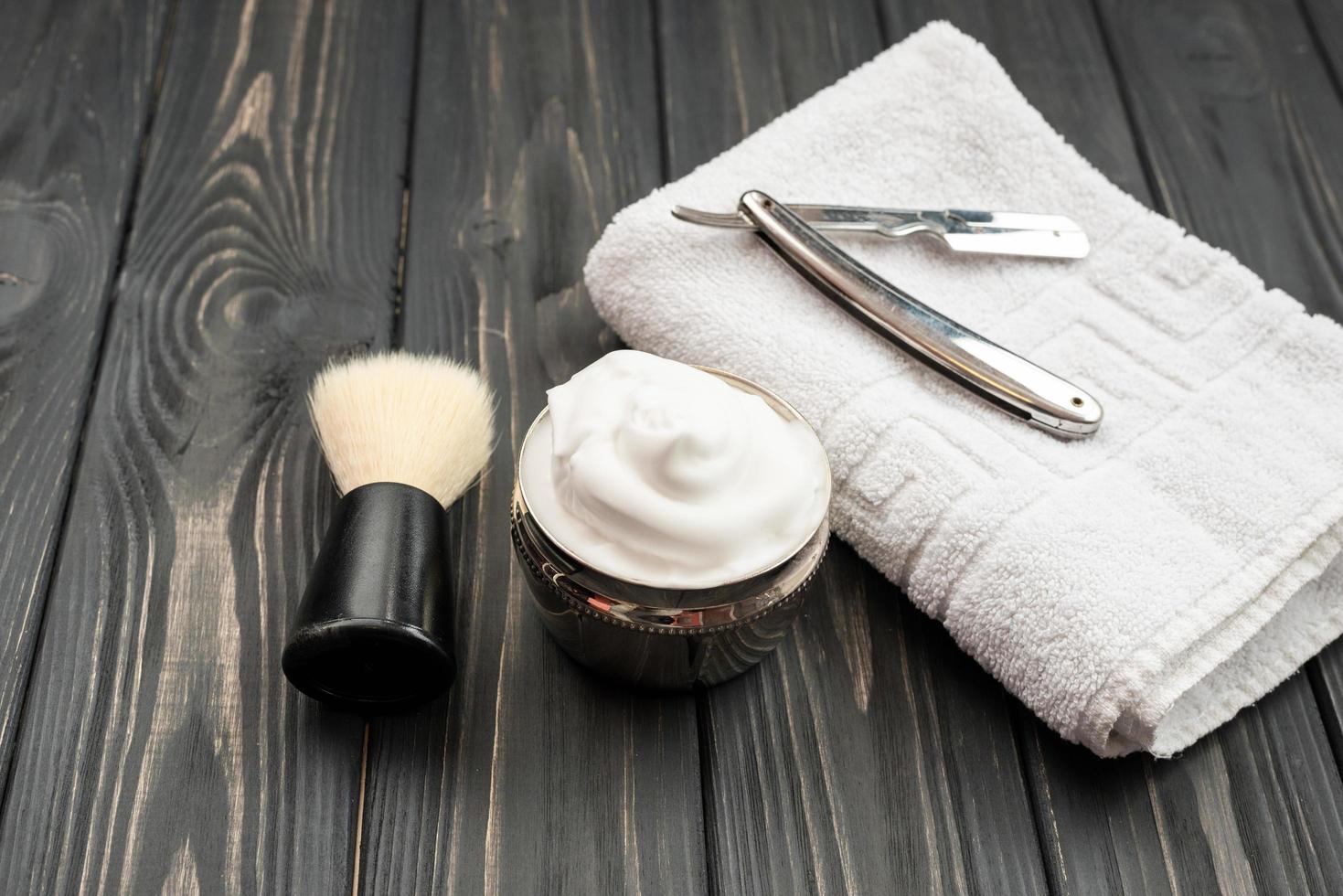 image d'outils de rasage, brosse, mousse, rasoir sur fond sombre et en bois photo