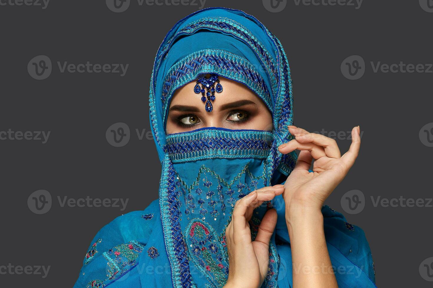 studio coup de une Jeune magnifique femme portant le bleu hijab décoré avec paillettes et bijoux. arabe style. photo