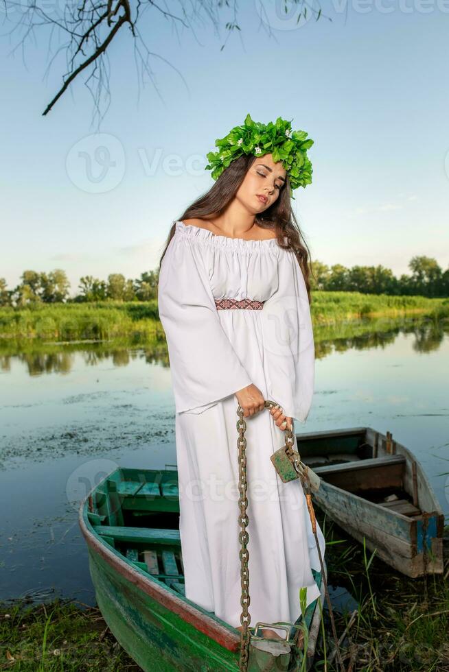 Jeune femme avec fleur couronne sur sa diriger, relaxant sur bateau sur rivière à le coucher du soleil. concept de femelle beauté, du repos dans le village photo