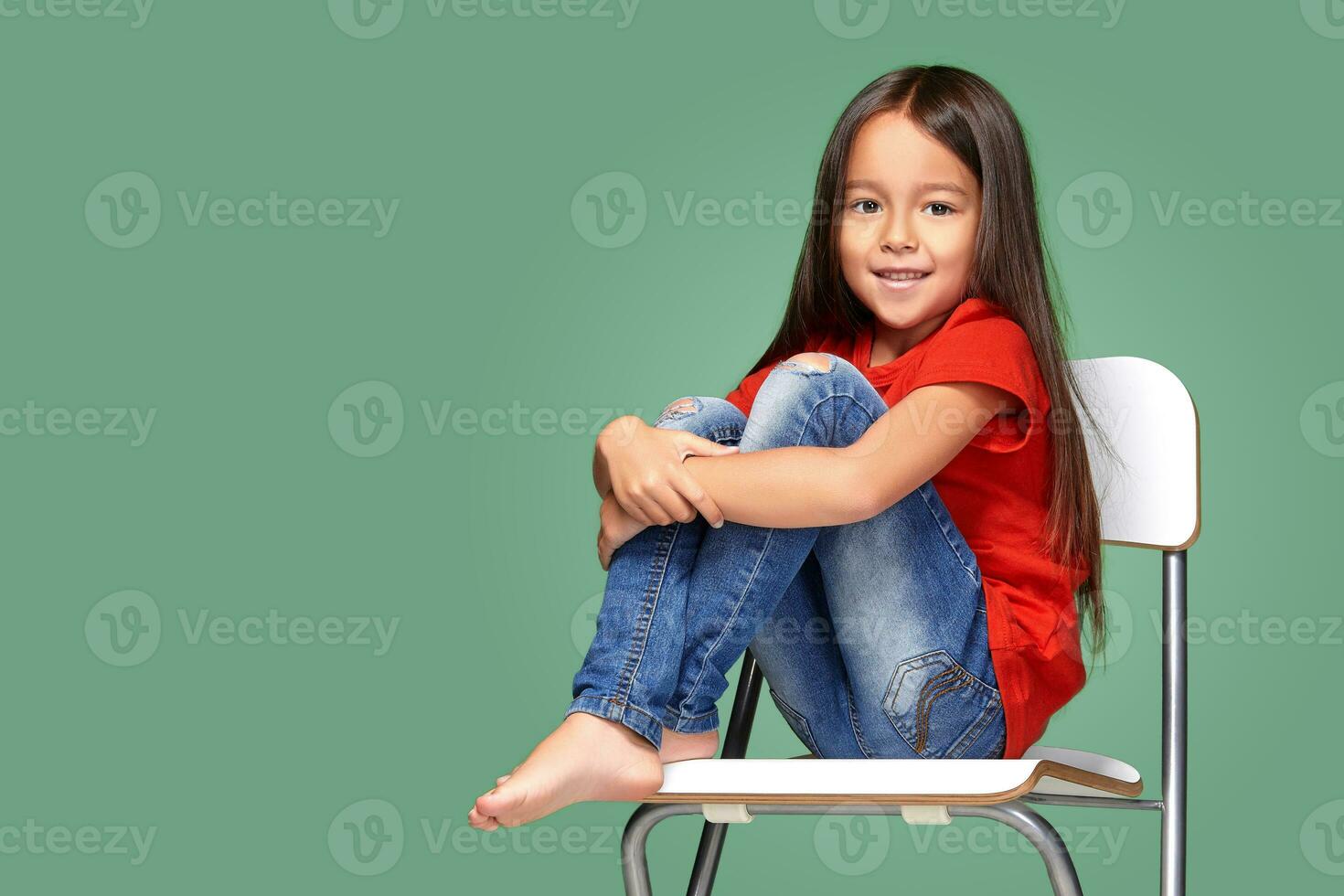 peu fille portant rouge t-court et posant sur chaise photo