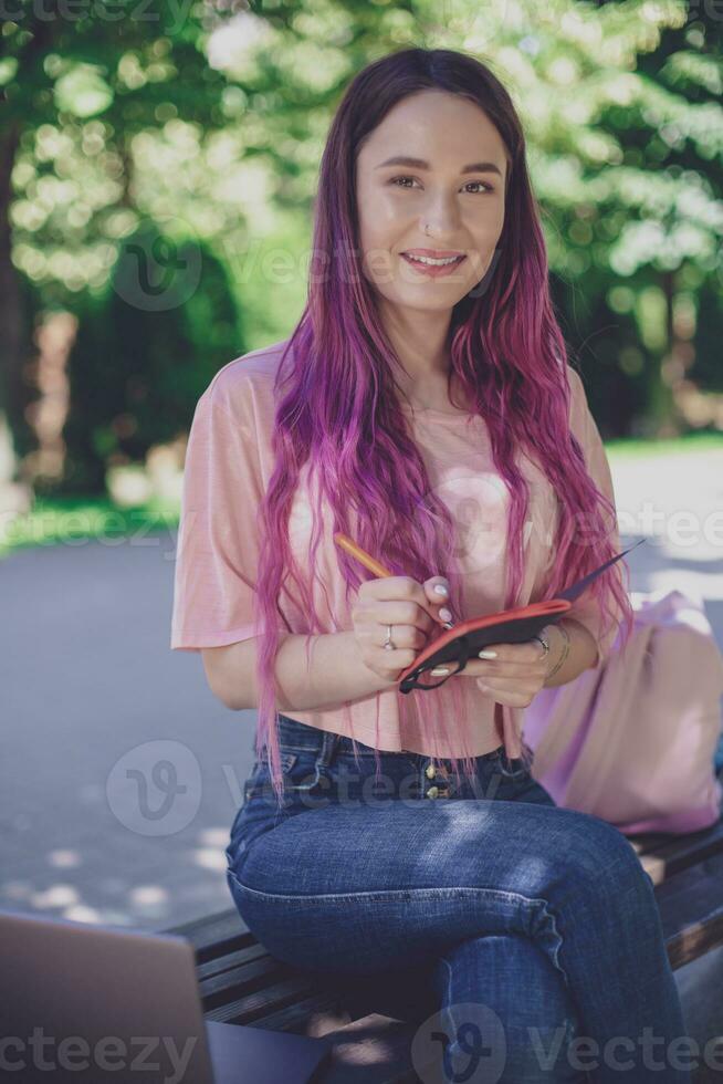 femme l'écriture dans une carnet séance sur une en bois banc dans le par photo