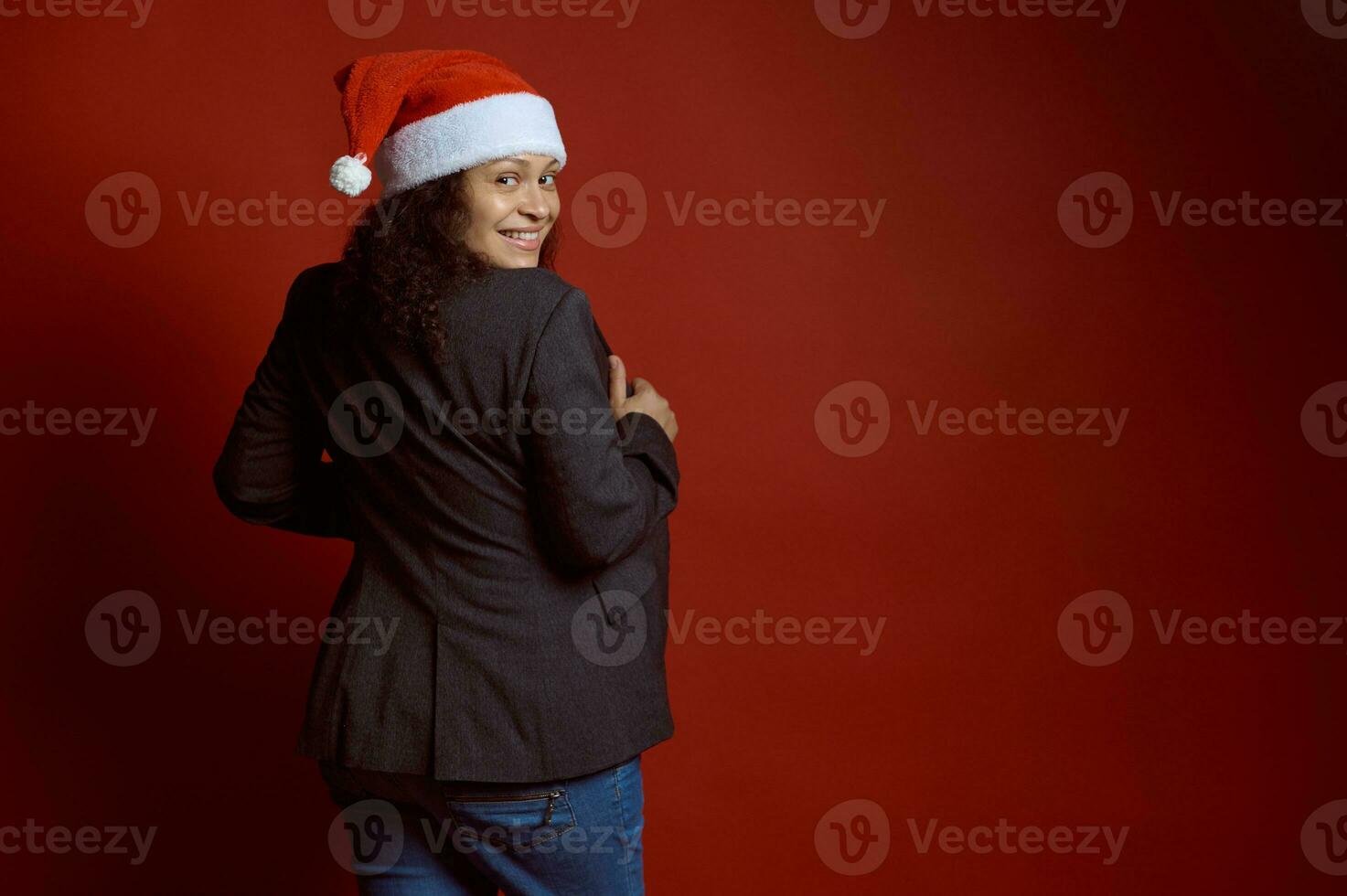 studio portrait de une multi ethnique Enceinte gravide femme sourires, à la recherche à caméra par sa épaules, isolé sur rouge photo