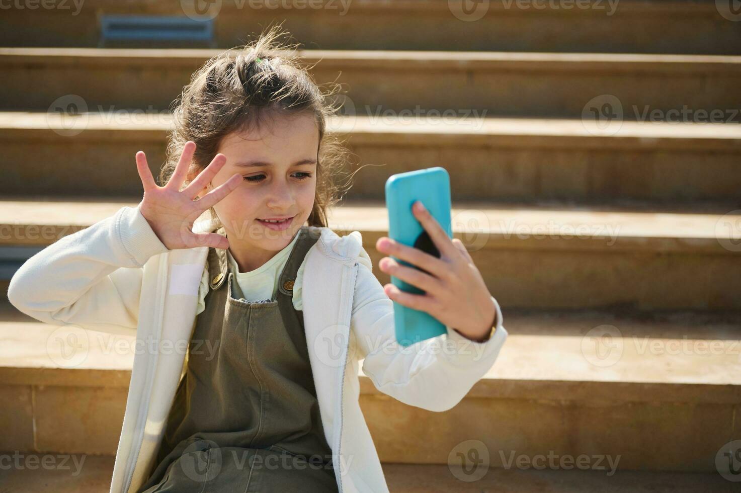 caucasien fille en utilisant téléphone intelligent, en ligne bavardage, communication, souriant agitant Bonjour avec main, parlant via vidéo lien, photo