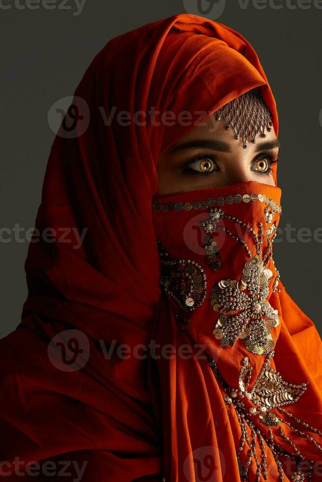 studio coup de une Jeune charmant femme portant le terre cuite hijab décoré avec paillettes et bijoux. arabe style. photo