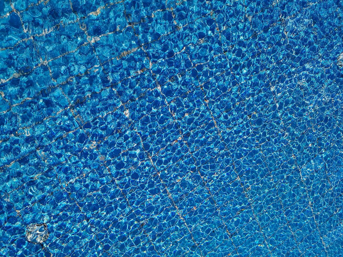 bleu l'eau ondulation dans nager bassin avec Soleil reflets photo