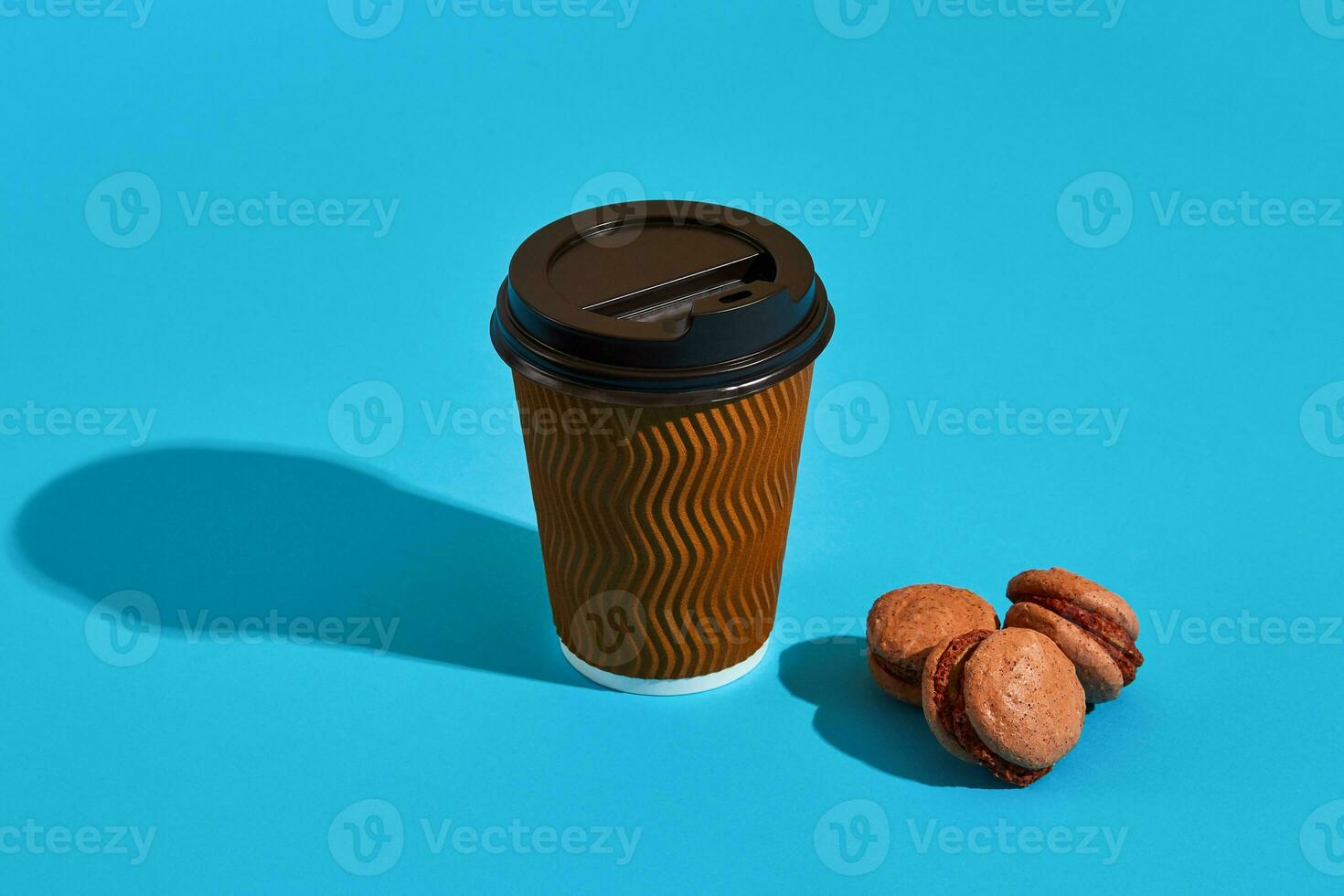 chaud café dans marron papier tasse avec noir couvercle et macarons sur bl photo