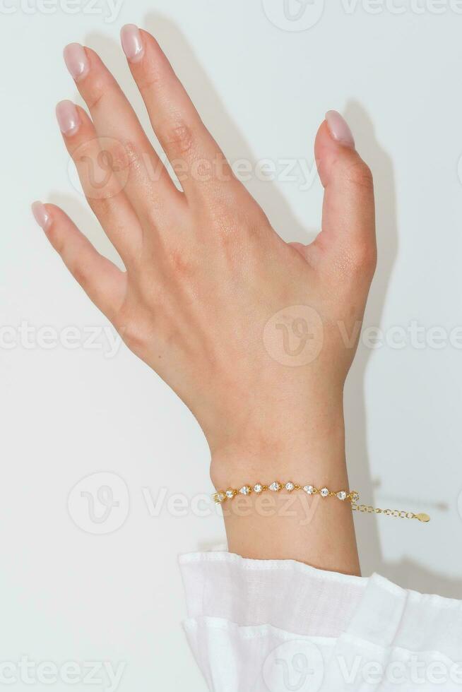 femme main et poignet portant d'or zircon scintillait bracelet ensemble contre une blanc Contexte. photo