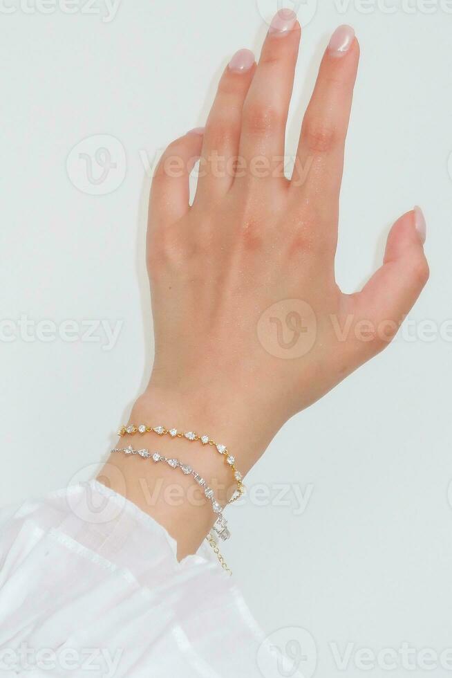 femme main et poignet portant zircon scintillait bracelets ensemble contre une blanc Contexte. photo