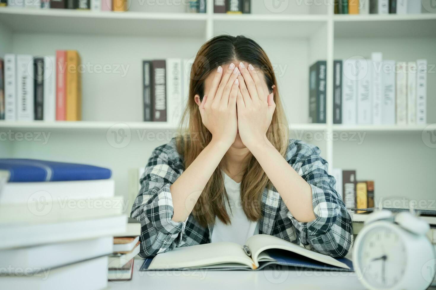 une étudiante asiatique a de l'anxiété à cause des examens, les femmes se préparent aux tests et apprennent les leçons à la bibliothèque. stress, désespoir, hâte, incompréhension lecture, découragement, attente, connaissance photo