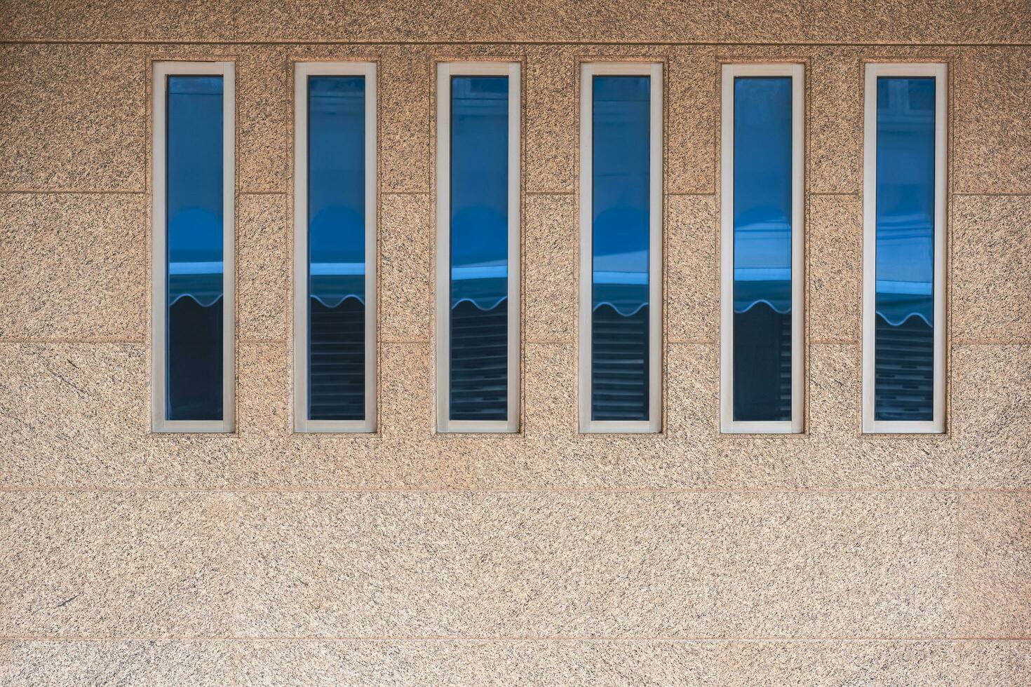 rangée de verre les fenêtres sur beige marbre mur à l'extérieur de ancien maison photo