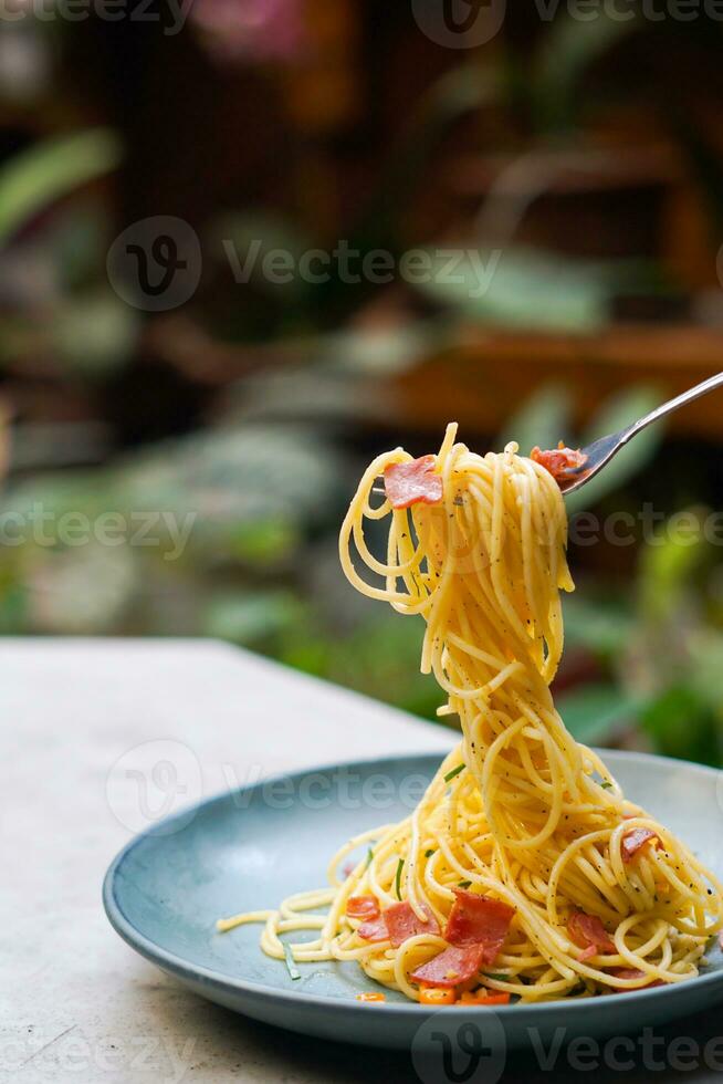 le main cette est levage le spaghetti sur le assiette photo