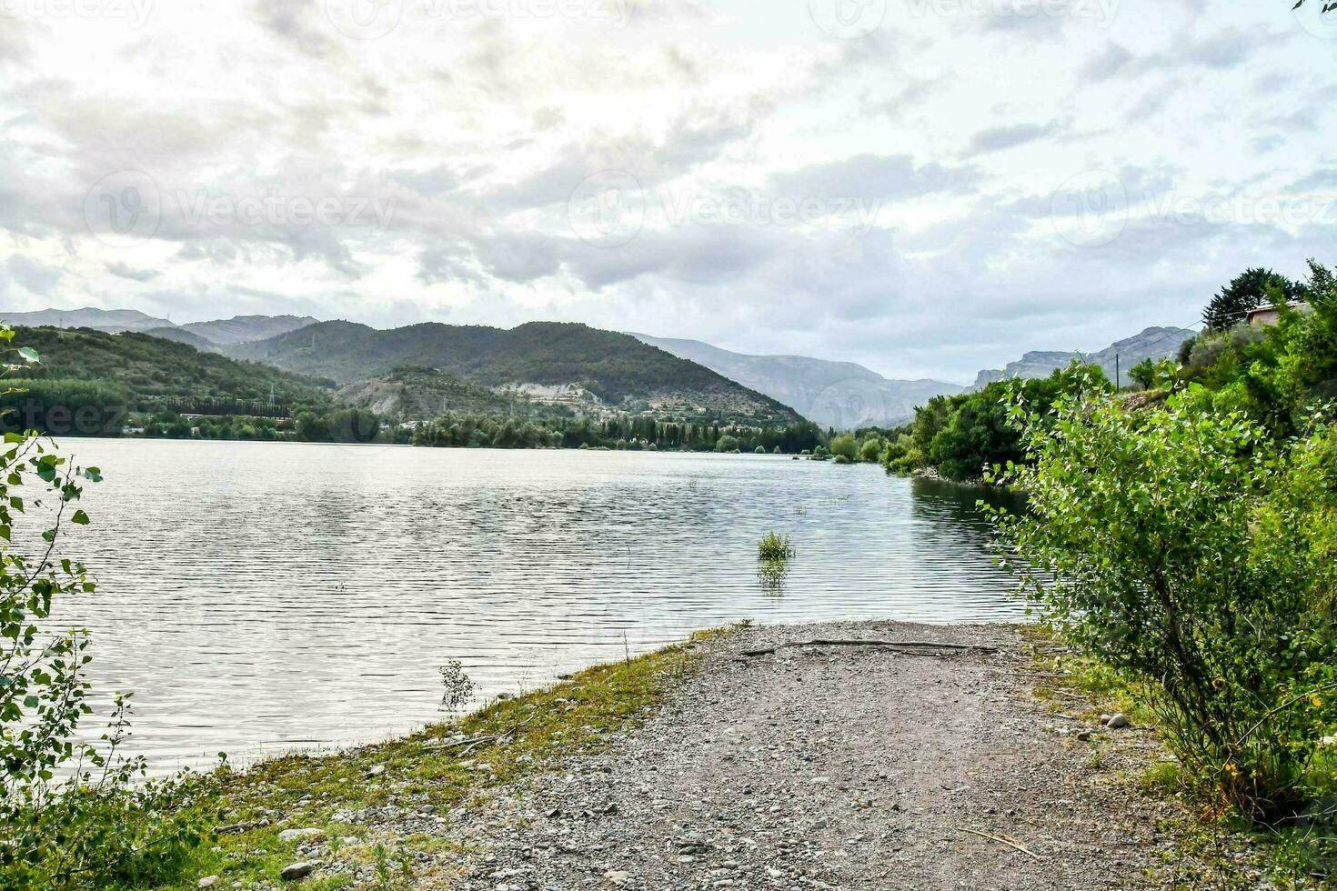 une chemin pistes à une Lac entouré par montagnes photo