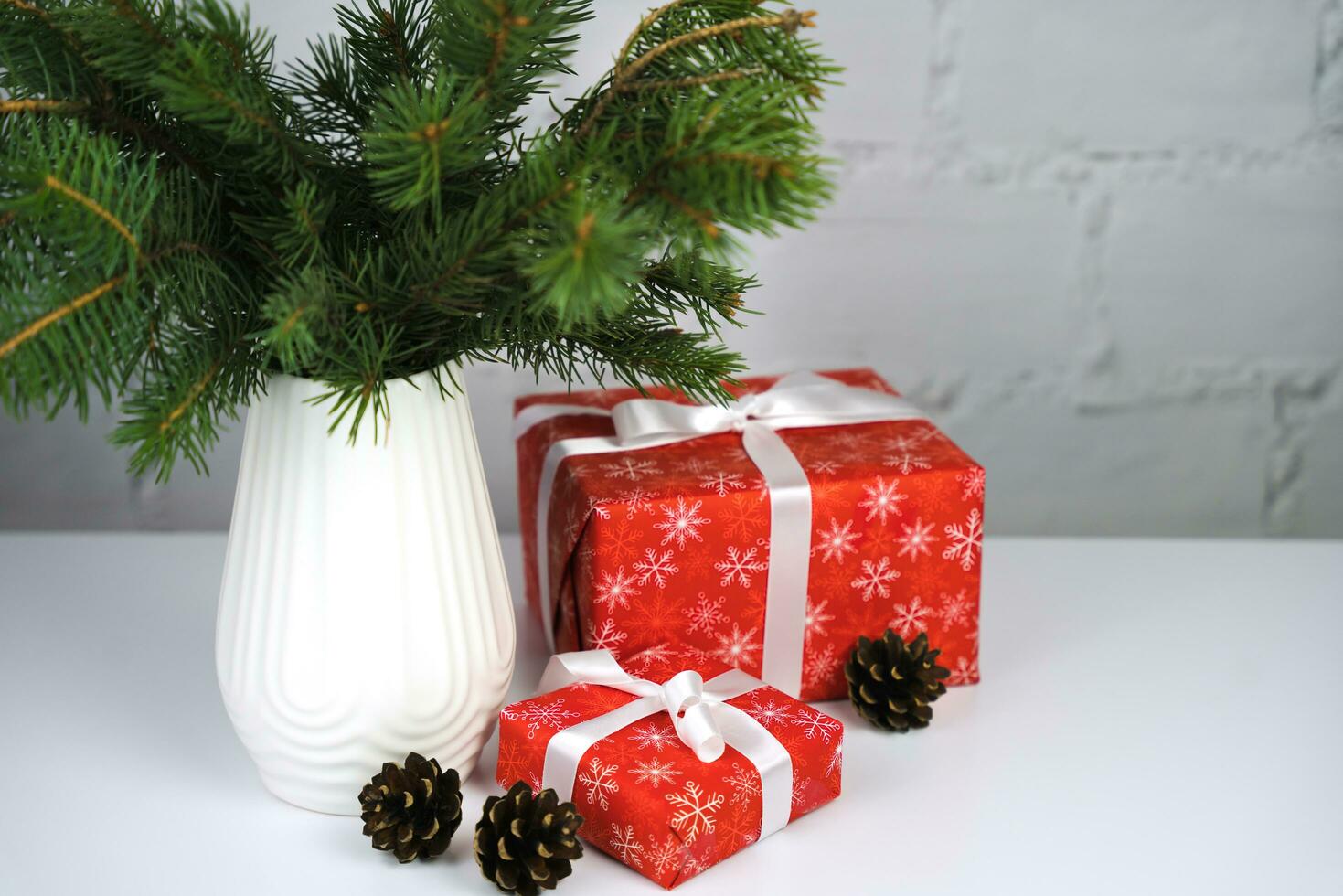 Noël cadeau des boites et épicéa branches dans une élégant blanc vase sur le tableau. cadeaux pour le Nouveau année et Noël. de fête ambiance. copie espace. photo