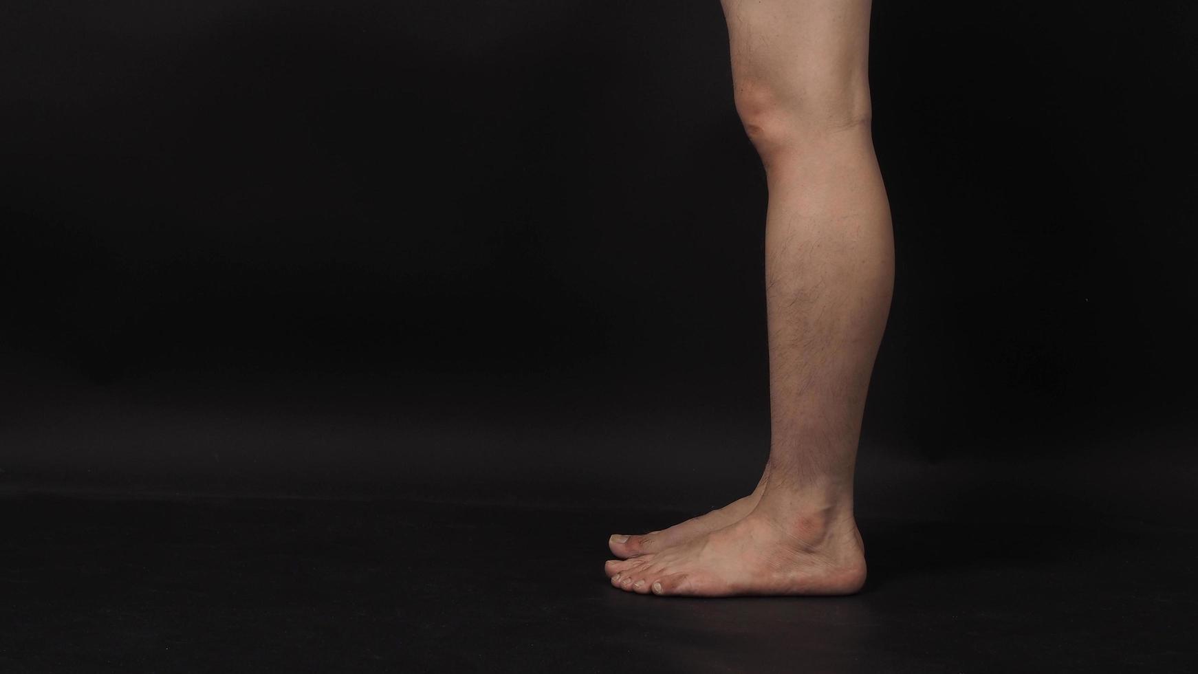 les jambes des hommes asiatiques et les pieds nus sont isolés sur fond noir photo