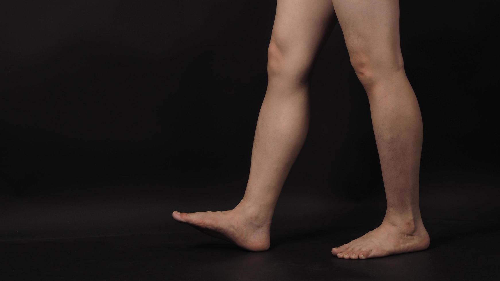 les jambes des hommes asiatiques et les pieds nus sont isolés sur fond noir photo