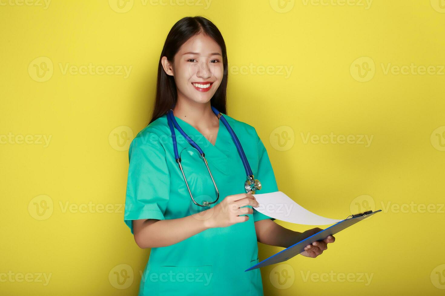 portrait de une magnifique Jeune femme dans une Jaune arrière-plan, asiatique femme portant une médecins uniforme fait du une souriant expression, une Jeune femme portant une médical stéthoscope a une amical expression. photo