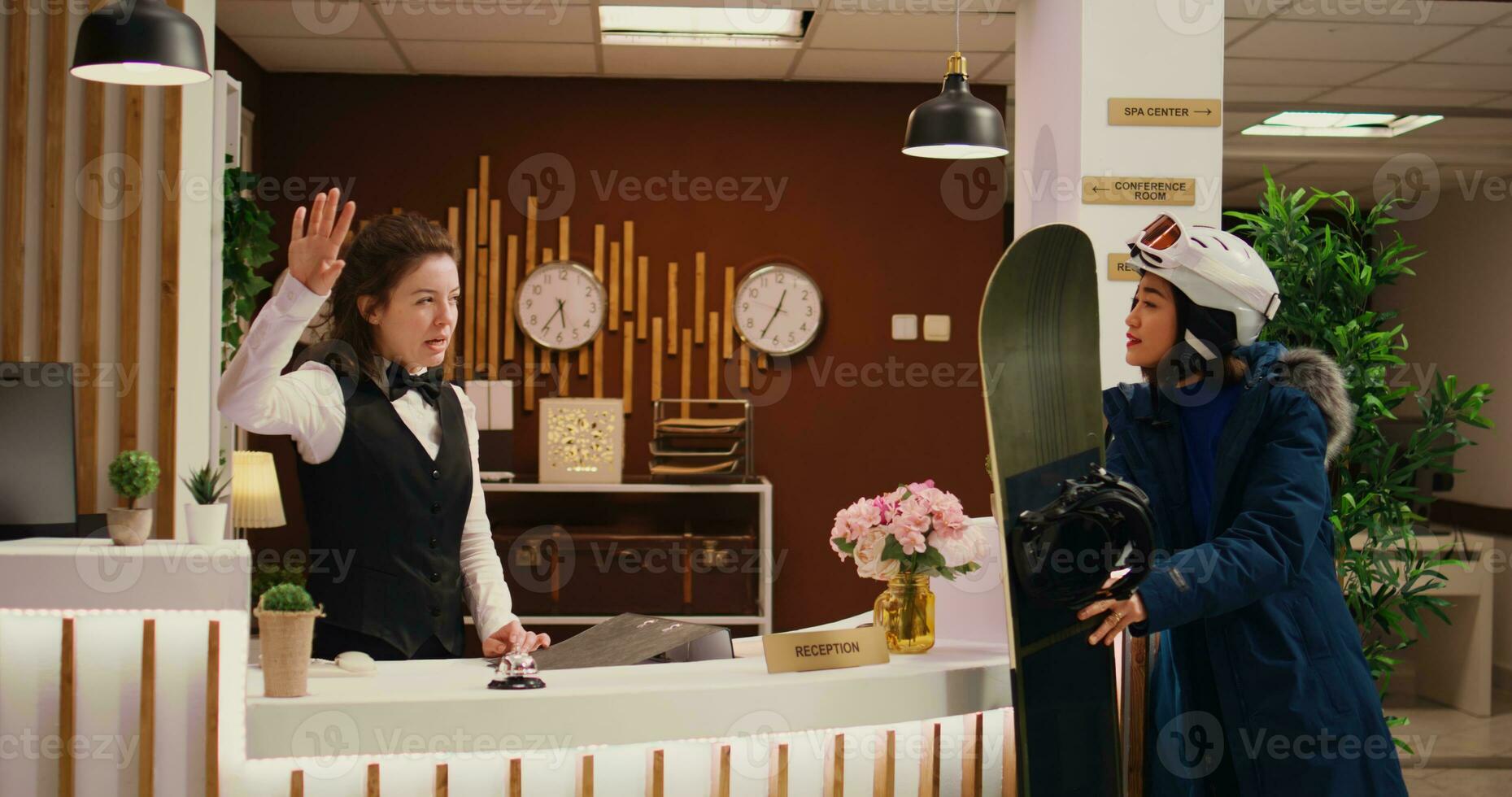 employé donne directions à asiatique fille, portion sa à aller ski sur neigeux pistes pendant l'hiver saison. femme réceptionniste conseiller client à propos extrême sport à ski station balnéaire. ordinateur de poche tir. photo