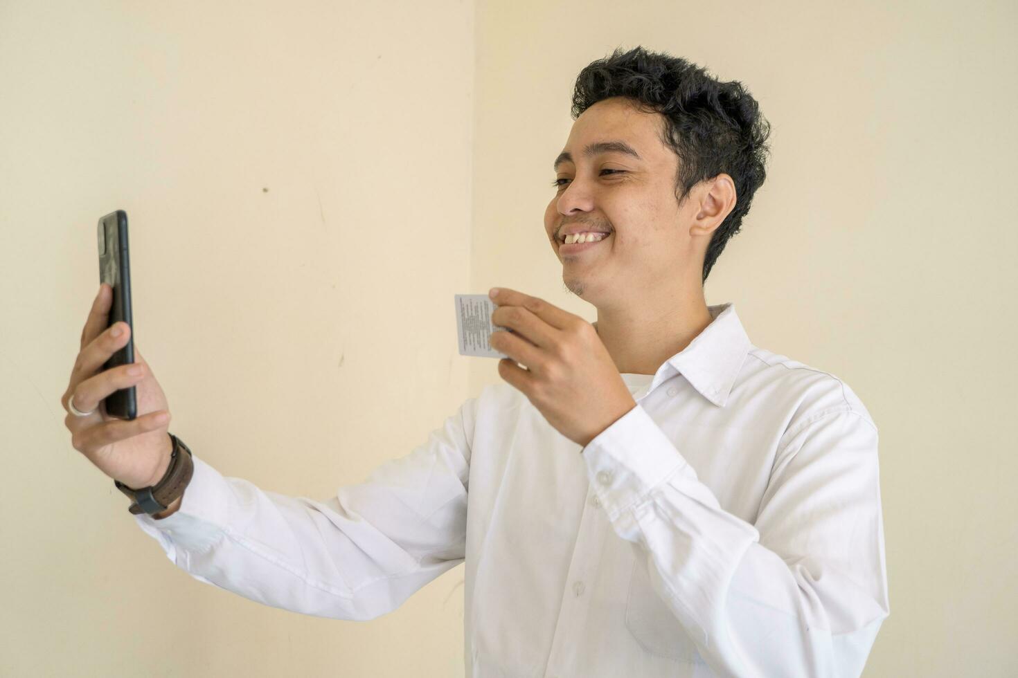 indonésien homme porter blanc vêtements avec selfie avec id carte à la recherche à caméra photo