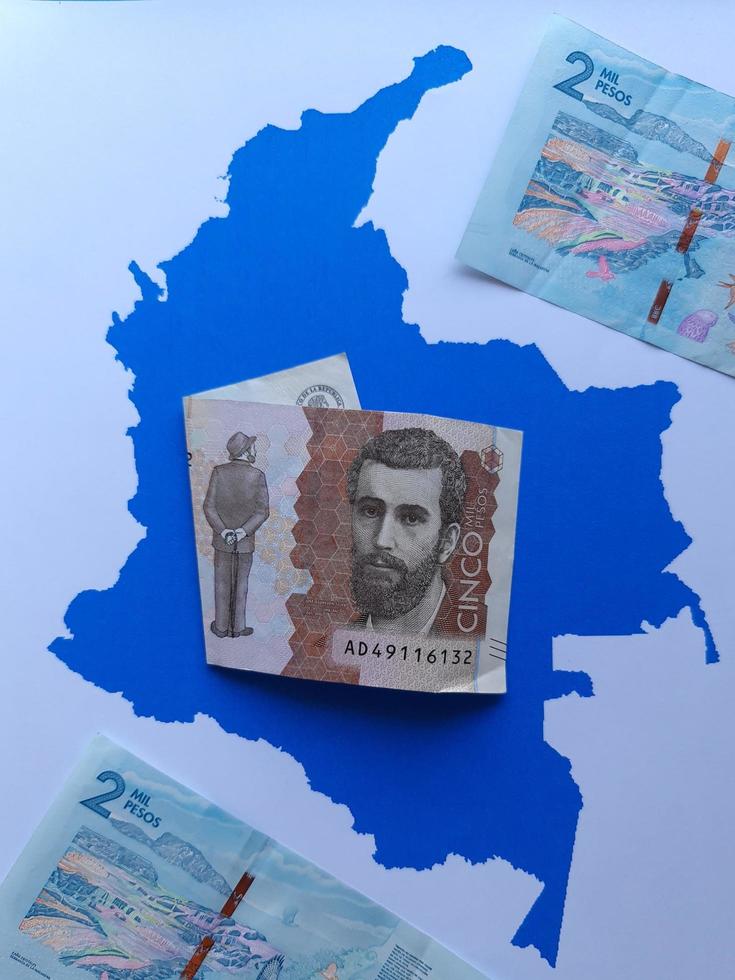 billets de banque colombiens et arrière-plan avec la silhouette de la carte de la colombie photo