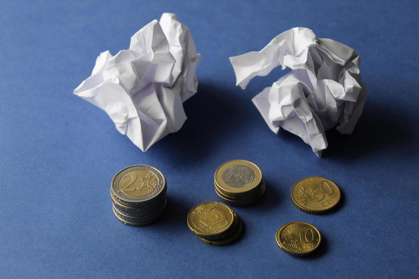 pièces européennes de dénomination différente et boules de papier froissé sur fond bleu photo