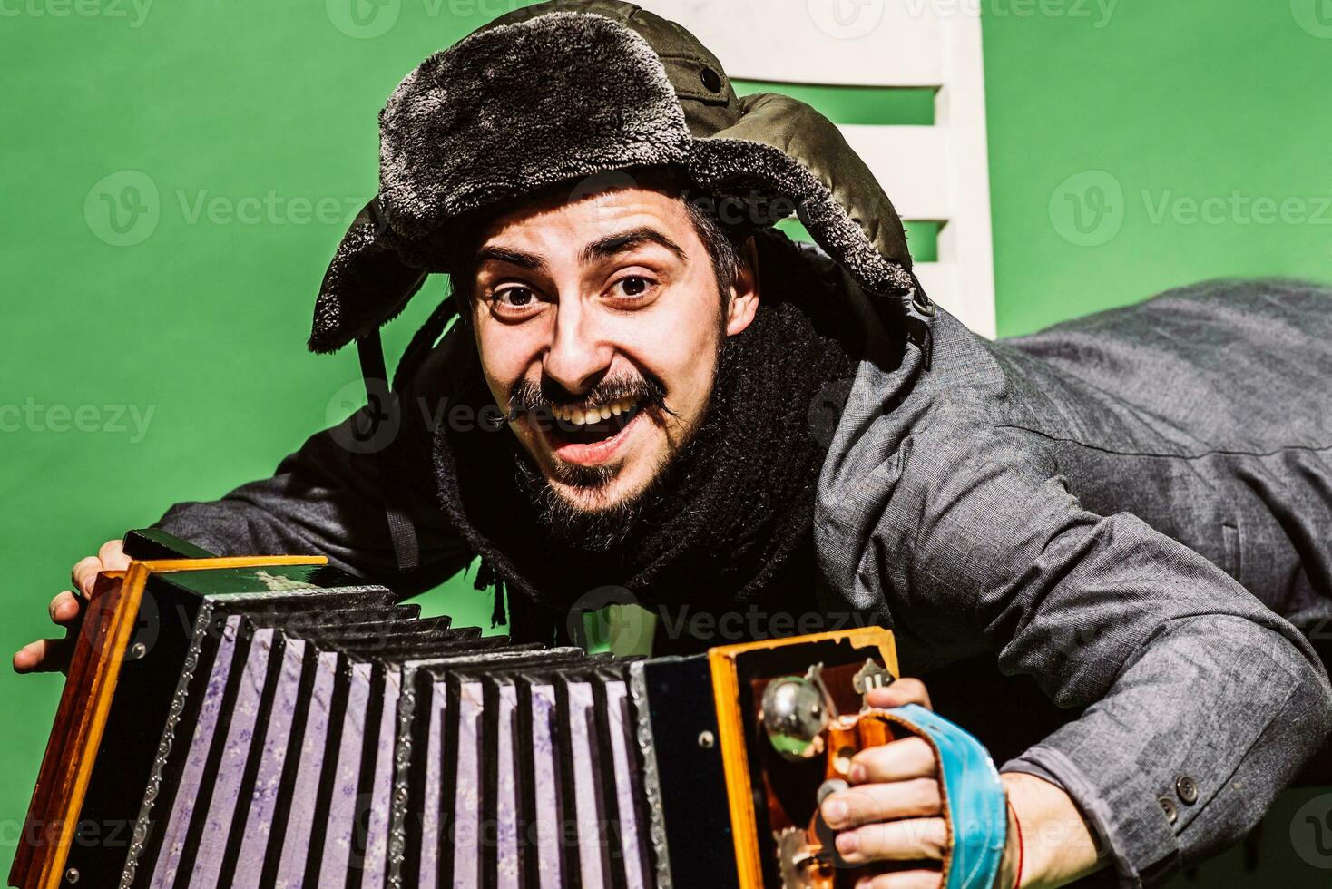 une très positif homme avec un accordéon posant dans le studio photo