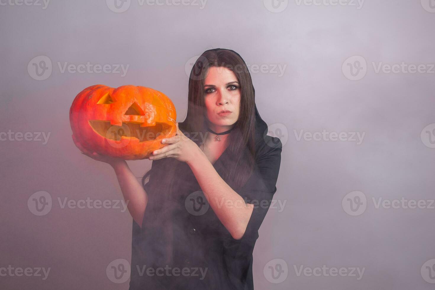 Halloween sorcière en portant une Orange citrouille jack o lanterne avec fumée photo