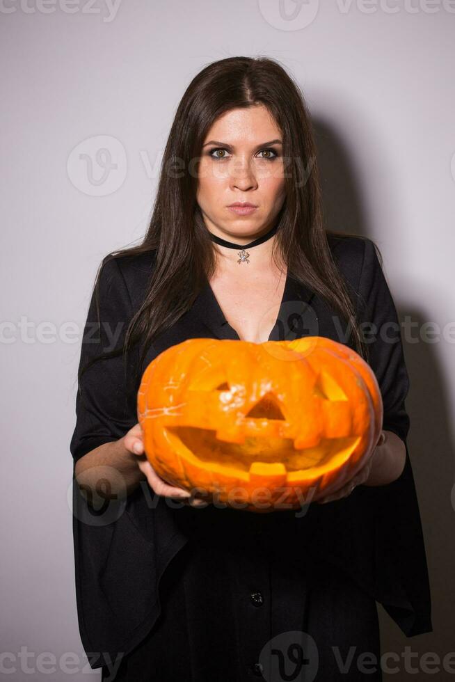 femme comme sorcière est permanent avec le citrouille dans le studio. Halloween et carnaval concept photo