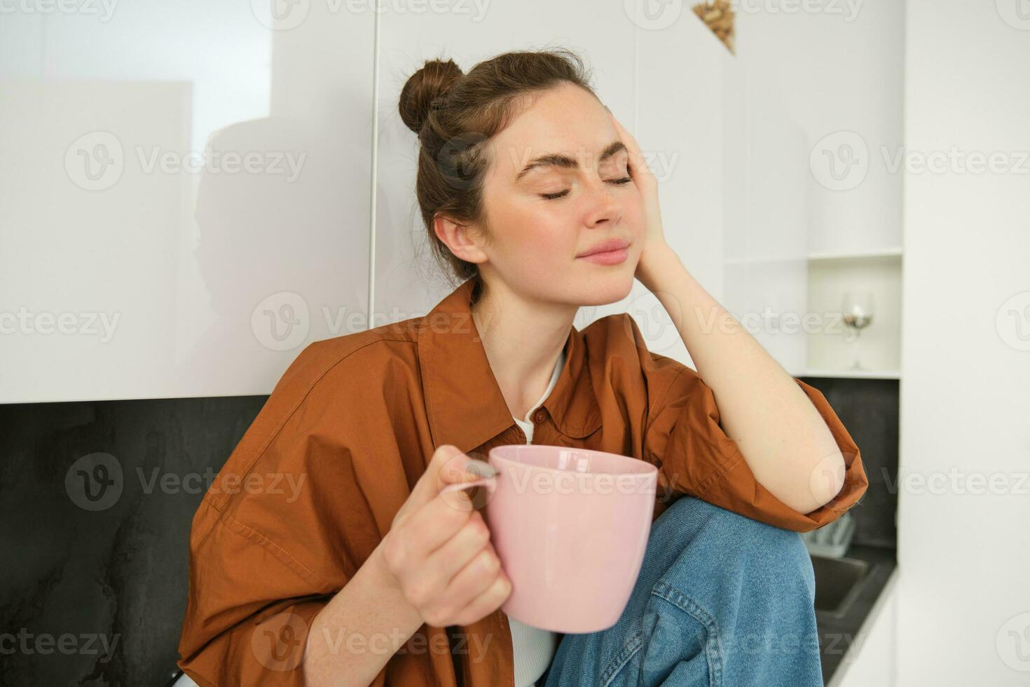 portrait de Jeune femme avec tasse de café, est assis dans cuisine et les boissons aromatique boisson à maison, détient thé agresser photo