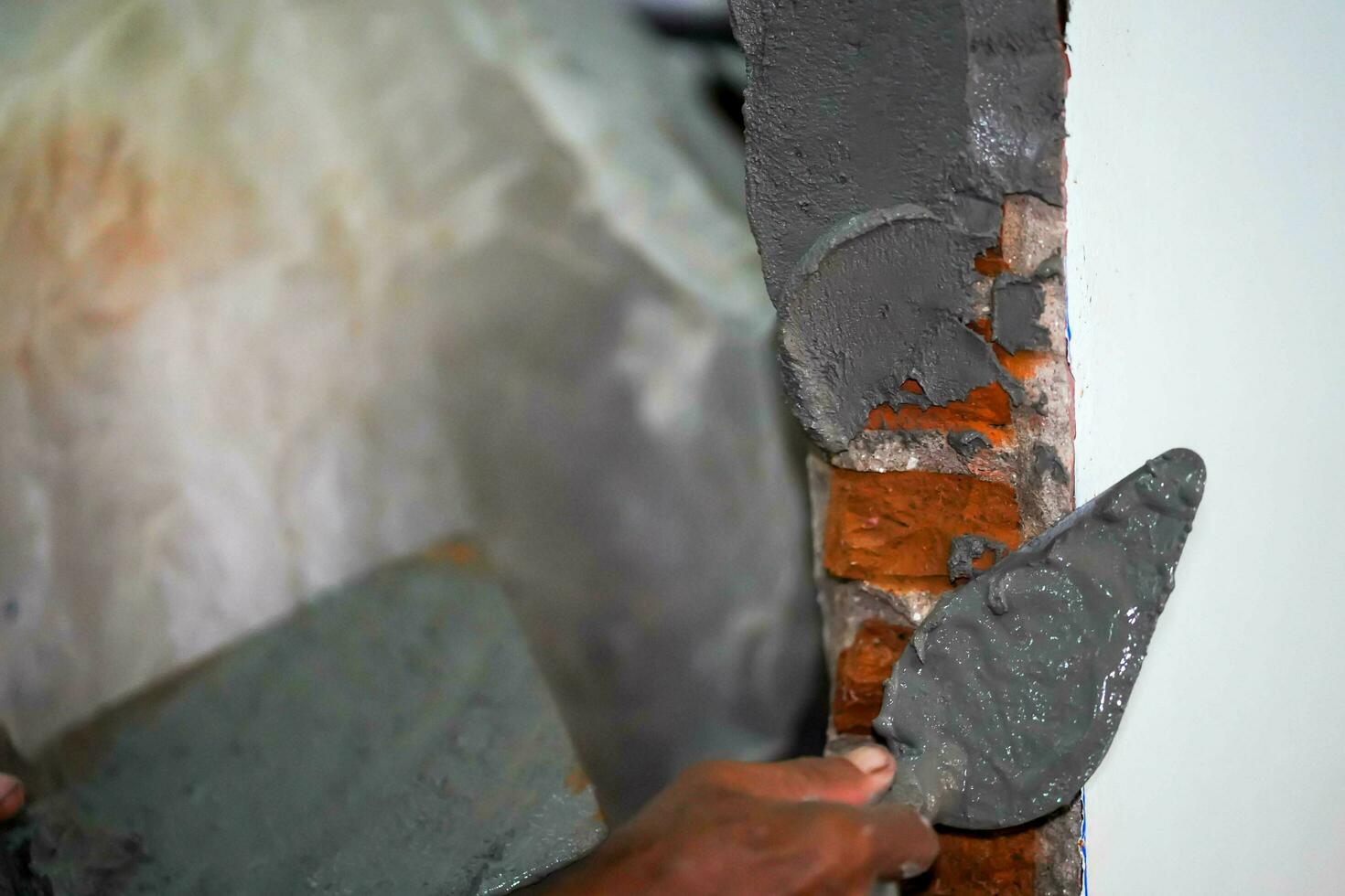 fermer mains de constructeur en portant mortier la poêle et plâtrage des murs avec ciment dans construction placer. photo