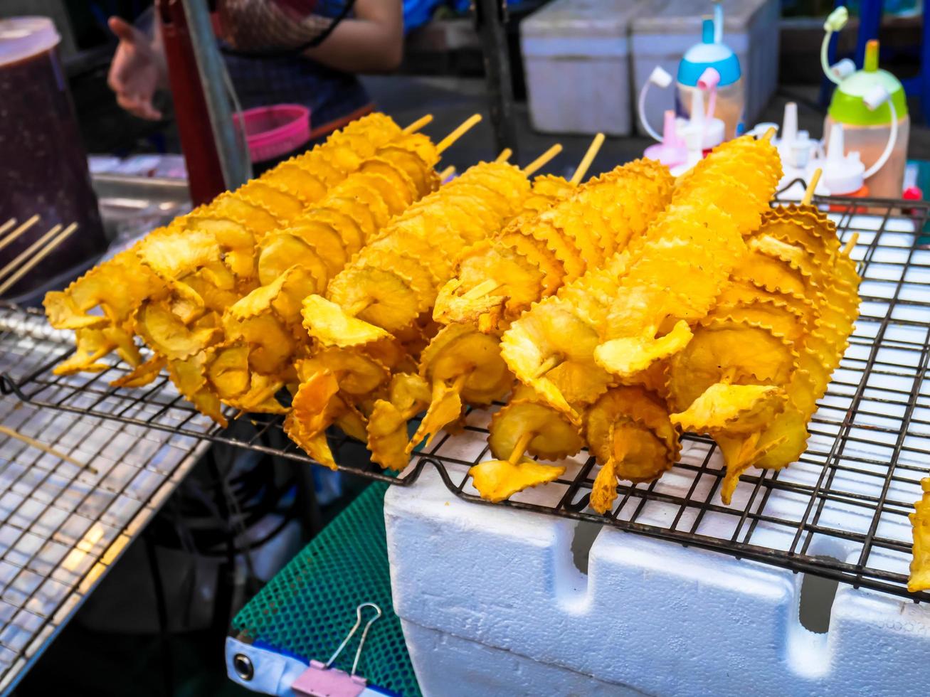 pommes de terre en spirale frites, sur des bâtons en bois, en spirale. vendre de la nourriture au marché. photo