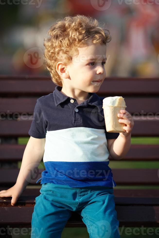 petit garçon s'assoit et mange une glace photo