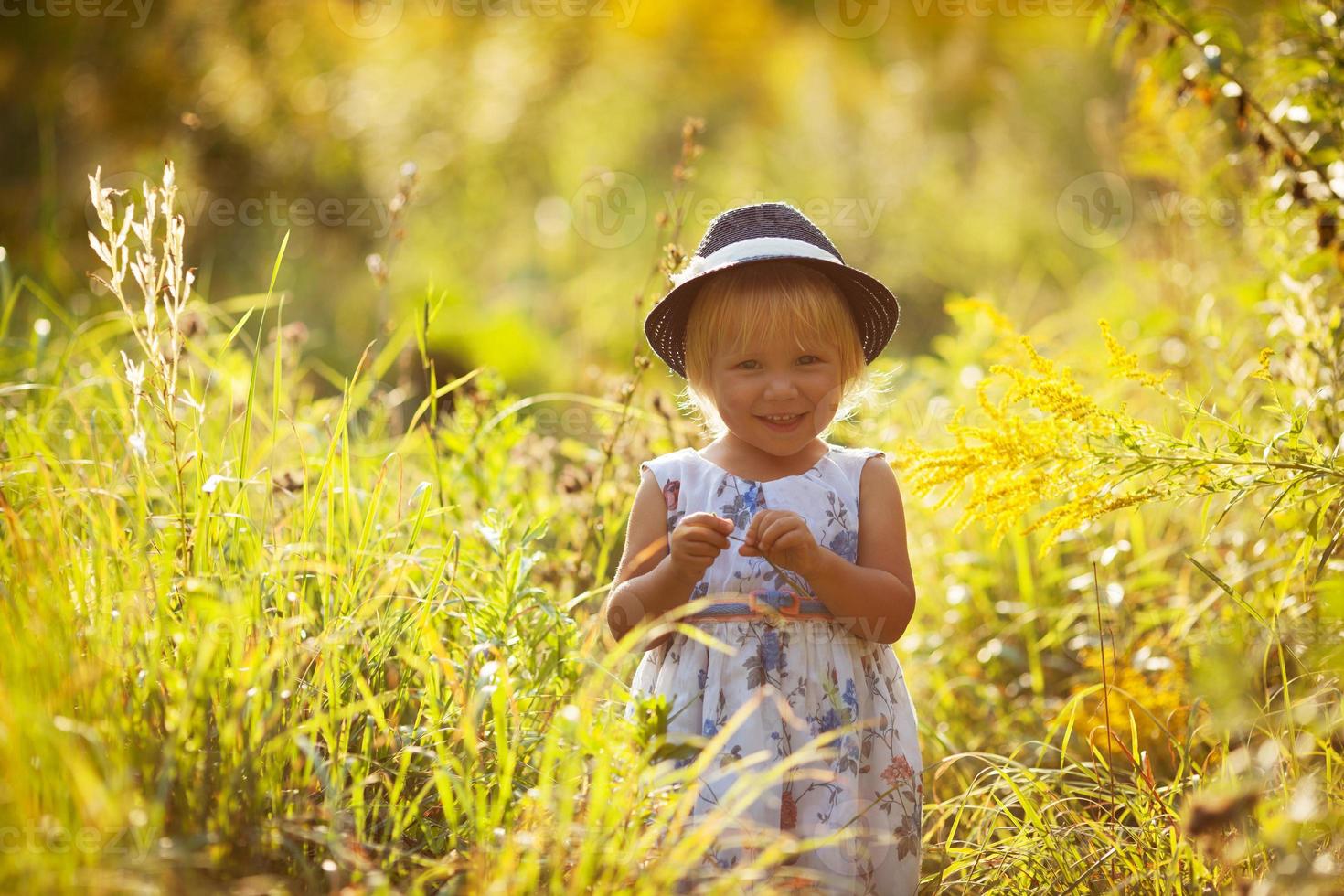 petite fille blonde dans une robe et un chapeau photo