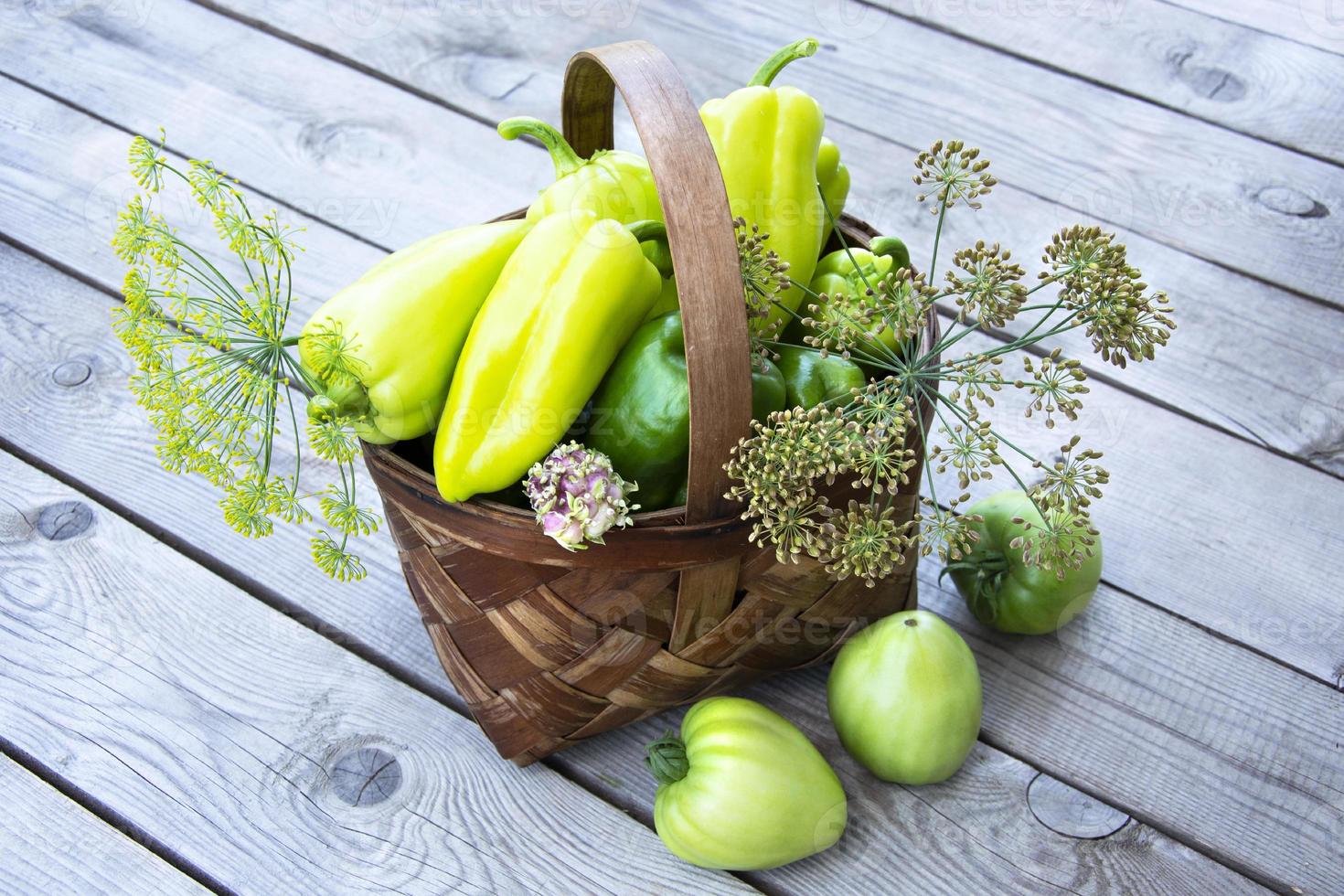 légumes dans le panier. un panier en osier avec des poivrons, des tomates et de l'aneth se dresse sur un fond en bois. photo