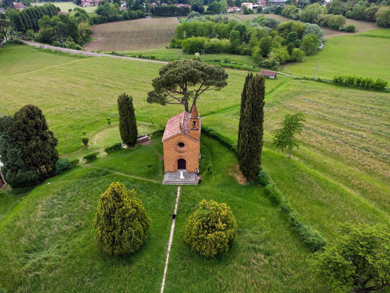 vue drone de couple fraîchement marié à l'église rouge de pomelasca photo