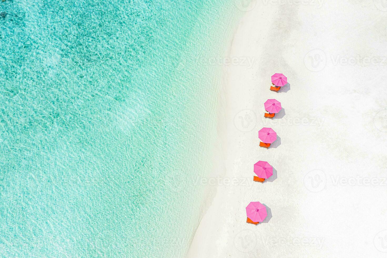 incroyable aérien vue de paradis plage paysage avec chaises longues et rose parapluies proche à incroyable tropique mer. blanc le sable et bleu cristal clair mer pour luxe été vacances vacances bannière Contexte photo