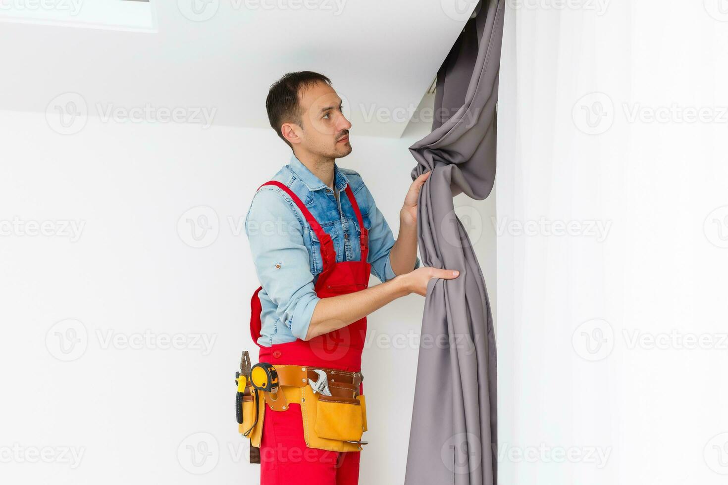 pratique homme Accueil installation et réparation un service technicien ou Accueil propriétaire pendaison rideaux pour le fenêtre traitement dans une Nouveau maison. photo