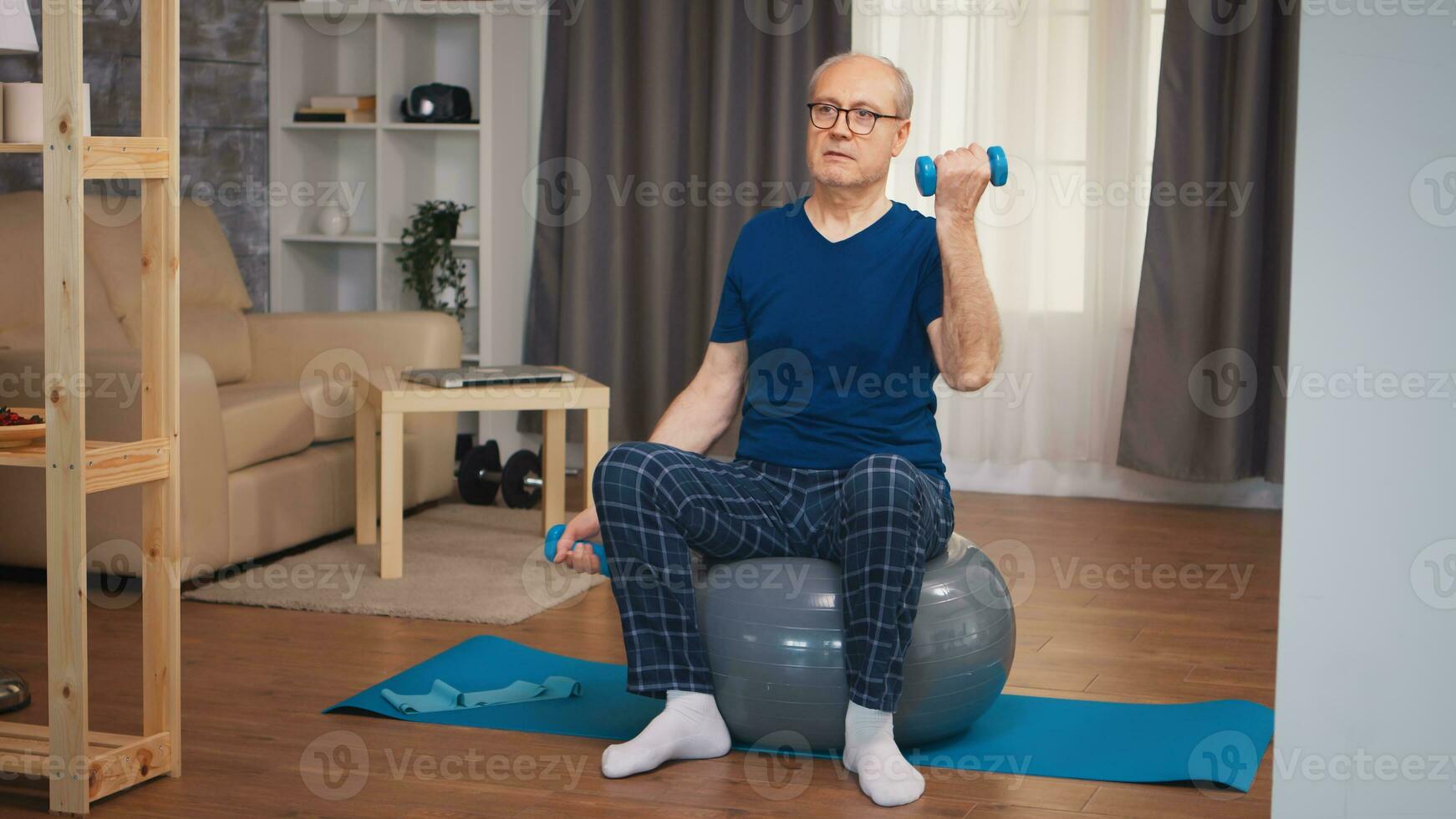 vieux homme Faire biceps formation avec haltères sur la stabilité balle. vieux la personne retraité en bonne santé formation soins de santé sport à maison, exercice aptitude activité à personnes âgées âge photo