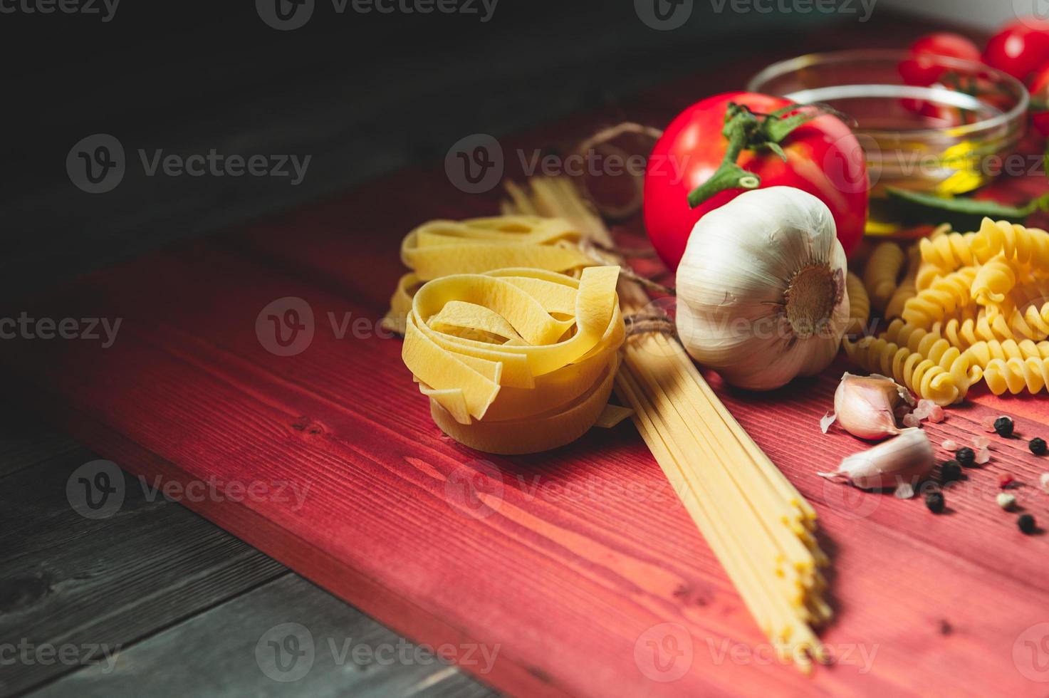 savoureux ingrédients de pâtes spaghetti italiennes appétissantes pour la cuisine de cuisine avec tomate, fromage parmesan, huile d'olive, fettuccine et basilic sur table marron en bois. cuisine italienne recette maison. vue de dessus photo