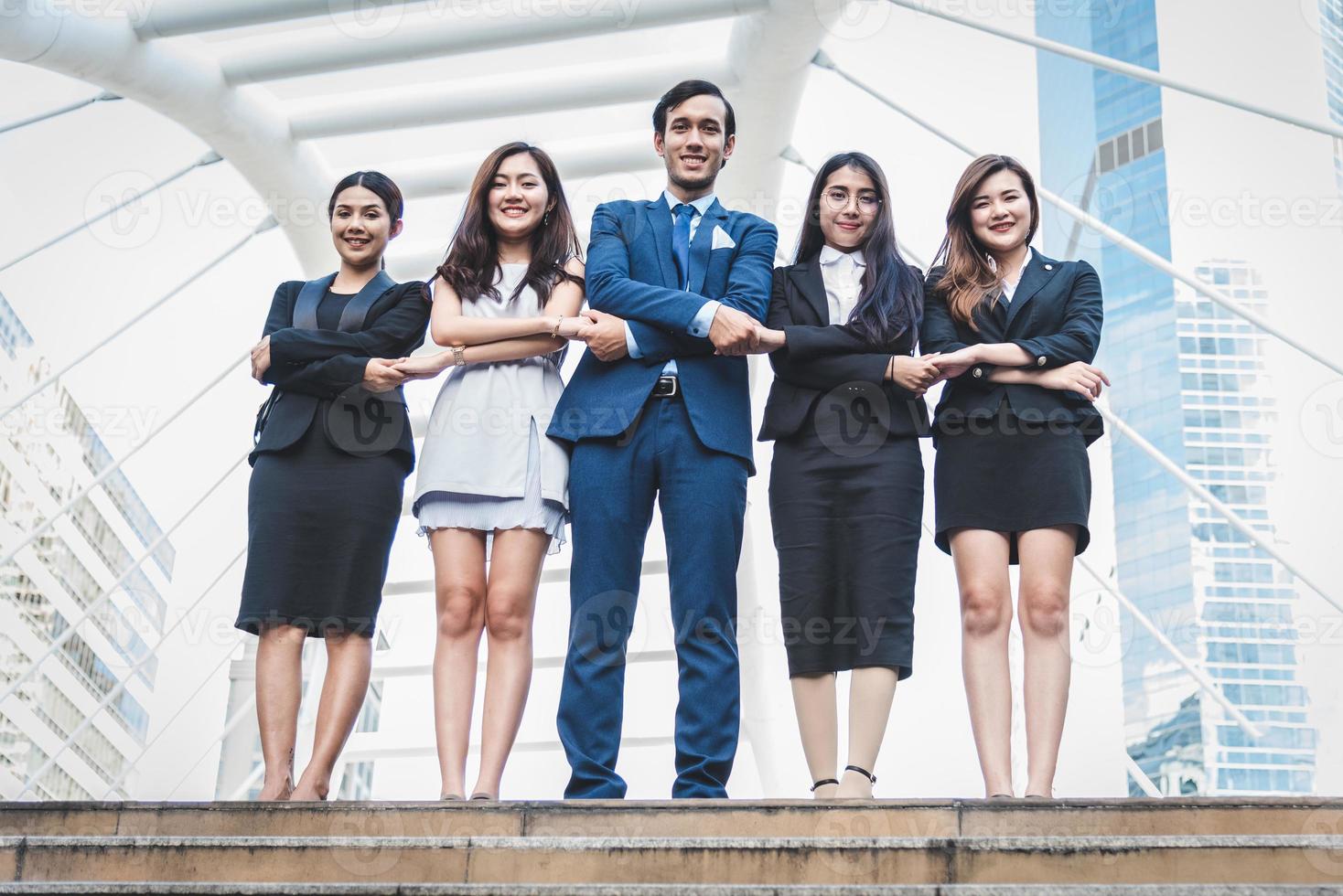 portrait d'un groupe de gens d'affaires prospère à l'extérieur en milieu urbain. hommes d'affaires et femmes d'affaires heureux debout en équipe dans un geste de satisfaction. groupe réussi de personnes souriant et regardant la caméra photo